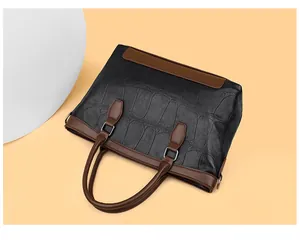 Detail of vintage crocodile texture leather handbag with brown handles and silver hardware