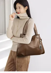 Detail of dark brown pebble leather tote bag with stitch paneling and pearl leaf pendant