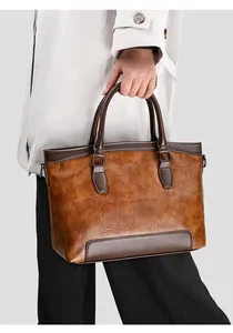 Detailed view of brown croc-embossed leather tote bag with contrast dark handles on a model