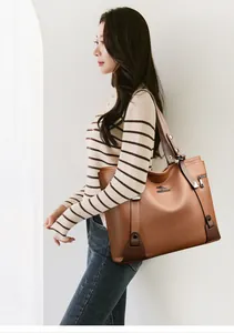 Classic brown leather tote bag with lychee texture and metallic rivet details on model