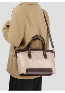 Close-up of a stone-pattern leather tote bag with brown handles on a fashion model