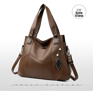 Side view of dark brown pebbled leather tote bag with metal logo and leaf pendant