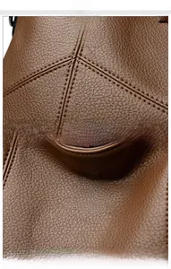 Detail of dark brown lychee textured leather with V-shaped stitching and silver kangaroo logo