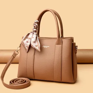 Elegant brown pebbled leather handbag with silk scarf and adjustable strap on neutral base