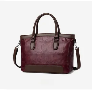 Detail of 45-degree side view showing burgundy crocodile embossed leather texture on bag