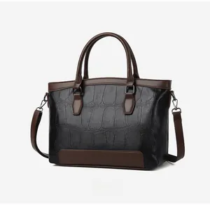 Close-up of the 45-degree angle of a black crocodile-texture leather handbag with brown trim