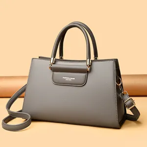 Sac à main élégant en cuir gris avec poignées rondes et détails dorés, style minimaliste