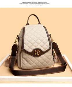 Detail of plum blossom metal clasp on beige quilted leather backpack with brown trim