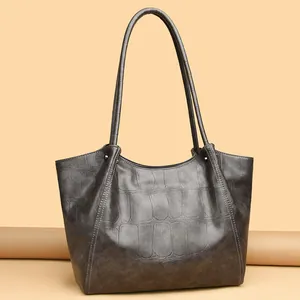 Deep grey tote bag with crocodile texture and long shoulder straps on beige background