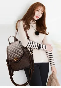 Detailed view of brown quilted leather backpack featuring a gold flower-shaped twist lock