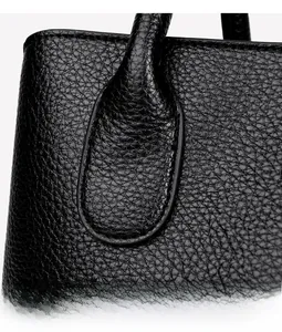 Close-up of premium black lychee leather grain and reinforced handle stitching details