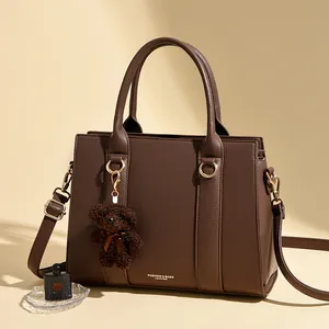 Sac à main en cuir marron foncé avec détails dorés et breloque en forme d'ours