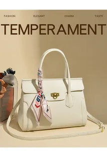 Detail of cream leather handbag with lychee texture and gold lock plus silk scarf handle