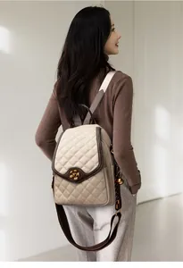 Detail of quilted beige leather backpack featuring a vintage bronze plum blossom clasp