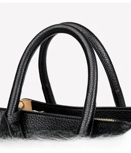 Close-up of black lychee leather handbag handle with stitching and gold zipper details