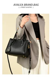 Close-up of black lychee grain leather tote with golden kangaroo charm and shoulder strap