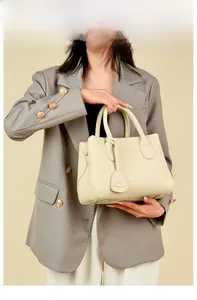 Detail view of off-white leather handbag with kangaroo pendant and protective metal feet