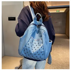 Detail of light blue denim backpack with punk style black cone rivets and fabric straps