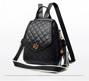 Detail of black quilted leather backpack with gold flower clasp and bell pendant charm