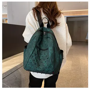 Detail of dark green floral backpack with black rivets and waterproof canvas texture