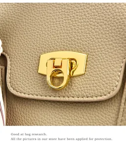 Detailed close-up of golden metal push-lock on premium lychee grain leather handbag