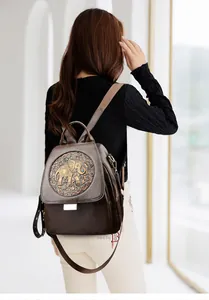 Detalle de mochila vintage de cuero marrón con elefante grabado y remaches metálicos
