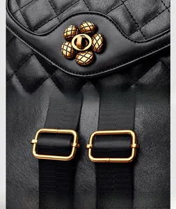 Detail of golden plum blossom lock and adjustable metal buckle on quilted leather backpack