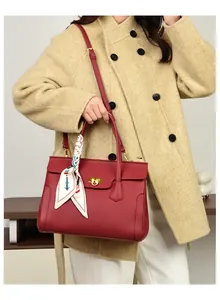 Detail of red pebbled leather handbag with gold twist lock and floral silk scarf accessory