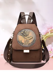 Detailed view of the embossed deer emblem and metallic rivets on brown suede backpack