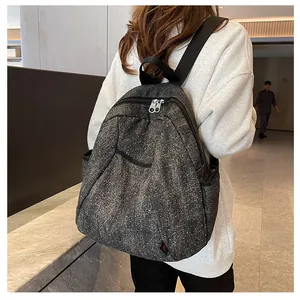 Detailed view of gray denim backpack with punk studs and metallic zippers worn by a model