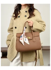 Brown lychee leather handbag detail with golden lock and patterned silk scarf accent