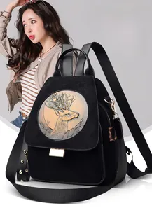 Close-up of suede backpack with golden reindeer embossed plate and rivet details