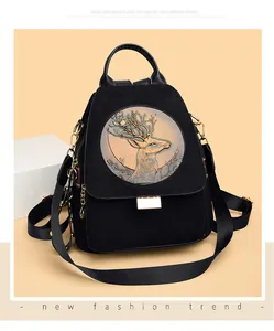 Detail of black faux suede backpack with vintage gold reindeer relief and metal hardware