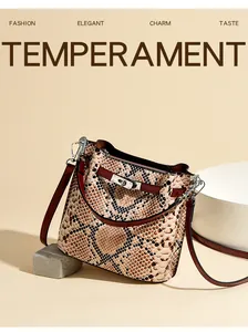 Detalle del bolso de cubo con estampado de serpiente y cierre de giro plateado