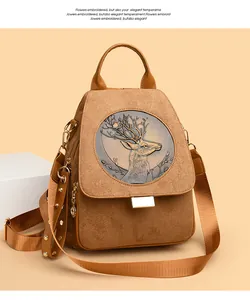 Macro detail of brown faux suede backpack featuring deer relief emblem and gold stud trim