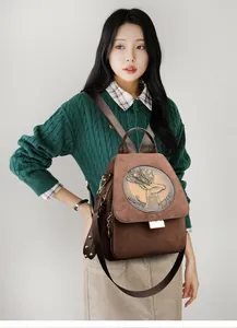 Detail of deer head embossed flap on brown faux suede backpack with metal hardware