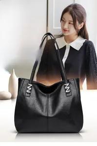 Close-up of black lychee grain leather tote bag with silver M-shaped metal buckle detail
