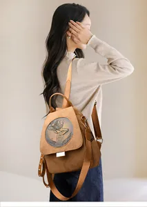 Detail of vintage suede backpack featuring a bronze deer head emblem and stud accents