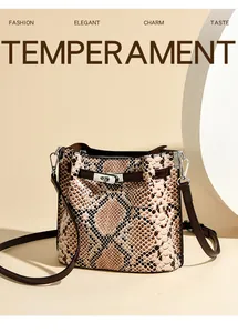 Detalle de bolso tipo cubo con estampado de serpiente, cierre plateado y correa de cuero
