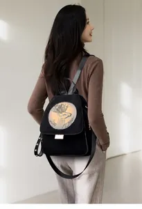 Detail of black suede backpack featuring a gold-toned deer embossment and rivet accents