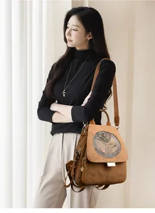 Detail of deer head relief and gold buckle on a brown suede convertible backpack