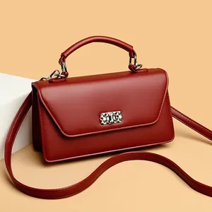 Bolso de hombro en cuero rojo con cierre geométrico plateado y asa superior de moda