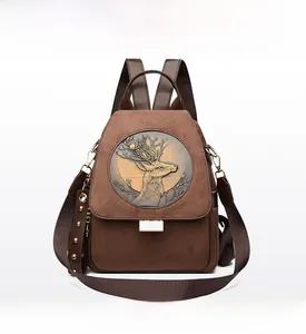 Front view of brown suede backpack featuring embossed deer motif and gold rivet details