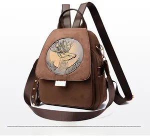 Detail of vintage brown suede backpack with stag relief emblem and golden rivets