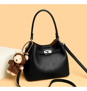 Detail of black pebbled leather bucket bag featuring silver twist lock and bear charm