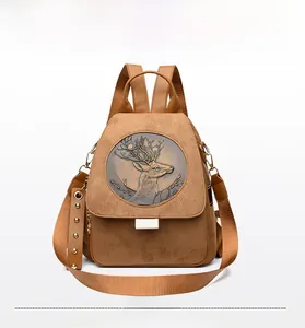 Detail view of suede backpack featuring deer relief emblem and studded shoulder strap