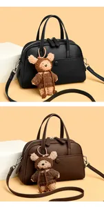 Close-up of litchi grain leather Boston bags in black and brown with plush bear charm