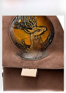 Detail of deer head relief and gold buckle on brown suede leather backpack