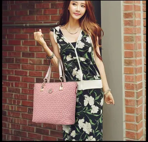 Close-up of pink tote bag with red patterns and gold logo held by a model