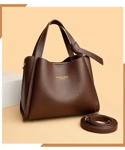 Dettaglio della pelle martellata marrone scuro e del logo dorato sulla borsa a mano